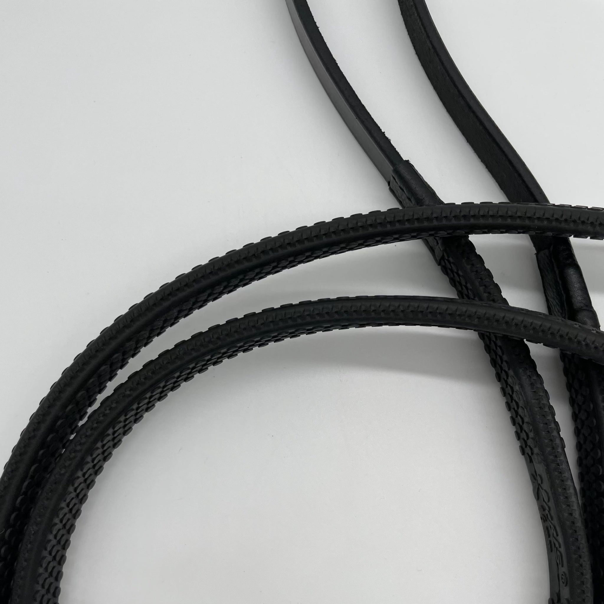 Ein breiter schwarze Gummi-Zügel mit Noppen von der Marke Ascot Reitsportartikel liegt auf einem weißen Untergrund. Dieser besteht aus strapazierfähigem, hochwertigem Material.